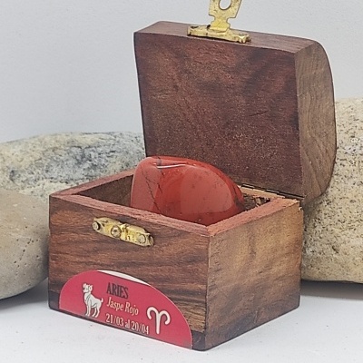 Caixa de madeira aberta com pedra vermelha e etiqueta Aries Jaspe Rojo.