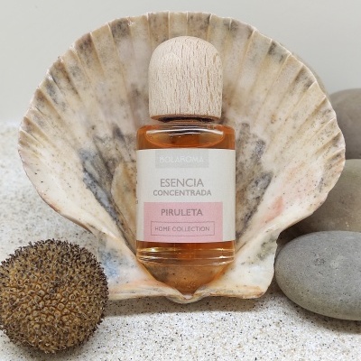 Frasco de essência concentrada PIrULETA dentro de concha sobre areia com pedras