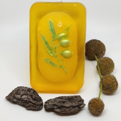 Sabonete amarelo com ramo verde e frutos dourados, casca de árvore escura e frutos peludos marrons