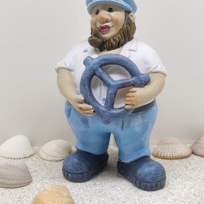 Figura decorativa de pescador segurando leme azul com conchas ao redor