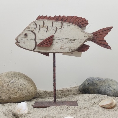 Figura decorativa de peixe em madeira com suporte metálico em areia com pedras e conchas.