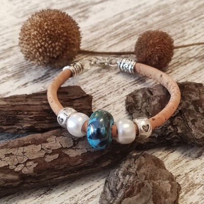 Pulseira com cordão bege e contas decorativas sobre madeira rústica