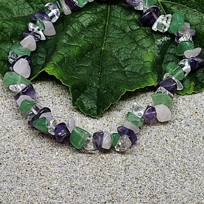 Pulseira colorida de pedras naturais sobre folha verde e superfície cinzenta