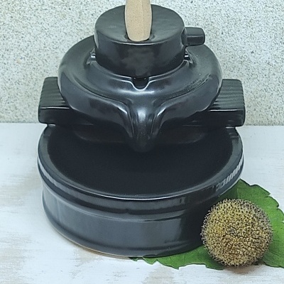 Incensário preto em cerâmica com suporte para cone de incenso e detalhes verdes ao lado