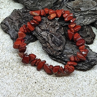 Pulseira de pedras vermelhas sobre casca de árvore e superfície clara