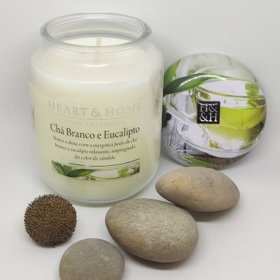 Vela aromática em vidro com tampa decorada, pedras lisas e bola texturizada.