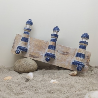 Cabide decorativo de faróis azuis e brancos na areia com pedras e conchas