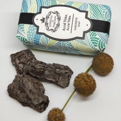 Sabonete Aloe Vera embalado com papel padrão colorido ao lado de cascas e bolas secas marrons.