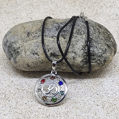 Colar com pendente prateado e pedras coloridas sobre pedra cinzenta