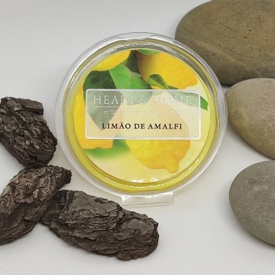 Produto redondo plástico com etiqueta de limões e texto, rodeado de cascas de árvore e pedras lisas