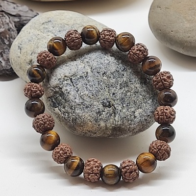 Pulseira de contas de madeira e olho de tigre sobre pedras cinzentas lisas
