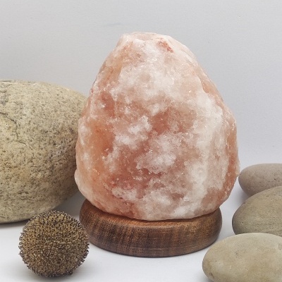 Lâmpada de sal rosa com base de madeira e pedras ao redor