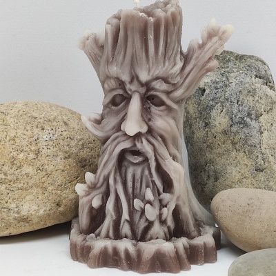 Vela em forma de árvore com rosto, com pedras ao redor