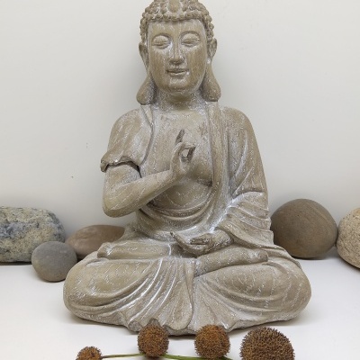 Estátua de Buda em pedra com pedras e flores secas