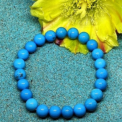 Pulseira azul em contas esféricas com flor amarela e areia azul