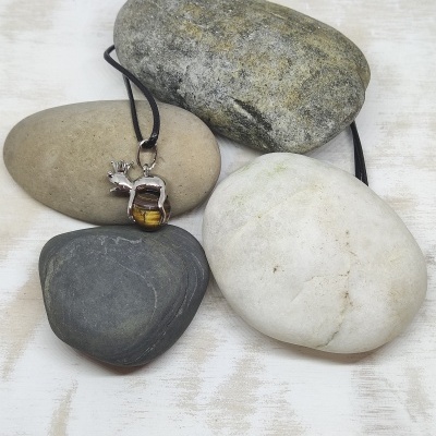 Colar com pendente de pedra em cordão preto sobre pedras naturais variadas