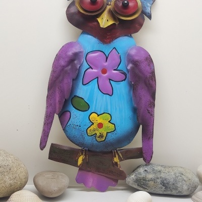 Estátua decorativa de coruja colorida com flores sobre branca e pedras