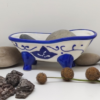 Banheira decorativa cerâmica branca e azul com pedras e elementos naturais