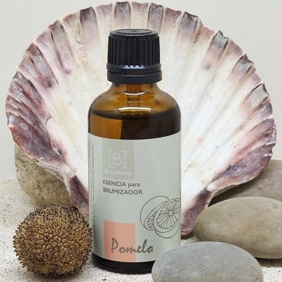 Frasco âmbar para esência de brumizador com etiqueta branca, ao lado de concha e pedras