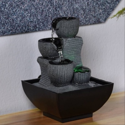 Fonte decorativa com copos cinza e base preta em madeira