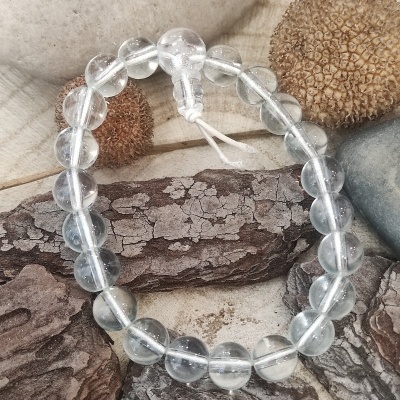 Pulseira de contas transparentes sobre pedras e superfície clara