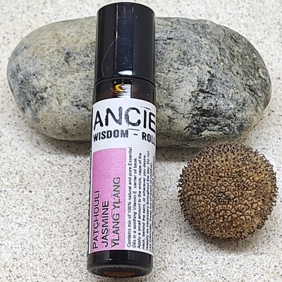 Frasco pequeno de vidro escuro com rótulo colorido ao lado de uma pedra e uma semente