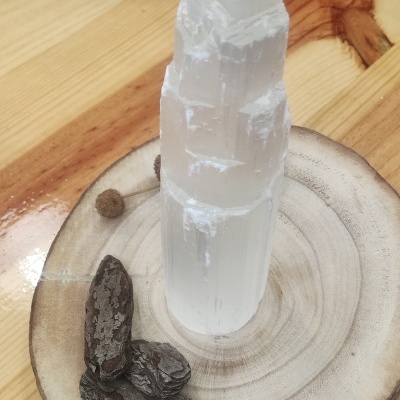 Cristal branco translúcido sobre base de madeira com dois objetos escuros ao lado