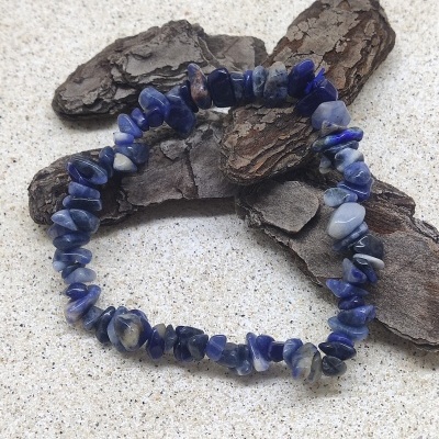 Pulseira azul e branca sobre superfície clara com casca de árvore