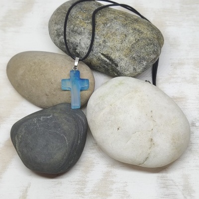 Colar com crucifixo azul em pedra pendurado sobre pedras
