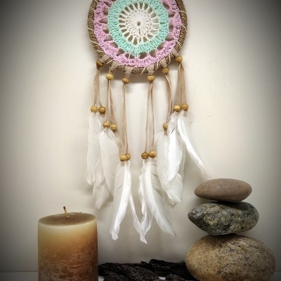 Filtro dos sonhos colorido com penas, vela, pedras empilhadas e pedaços de casca