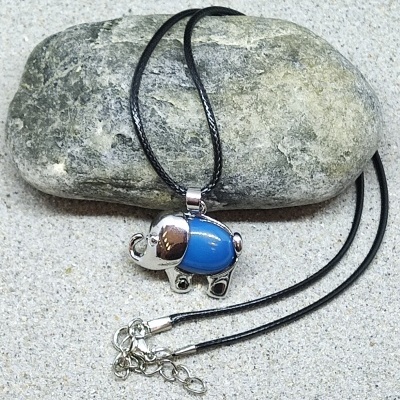 Colar preto com pendente elefante prateado e azul sobre pedra cinza