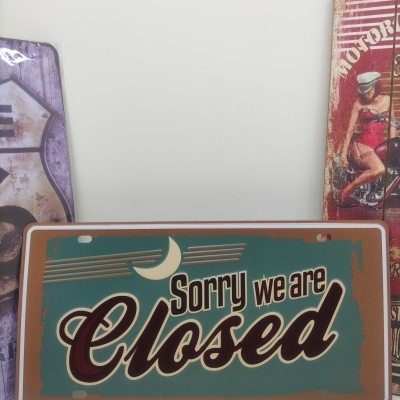 Placa metálica verde com texto 'Sorry we are Closed' em castanho e branco