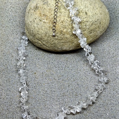 Colar de pedras transparentes com fecho prateado sobre pedra beige