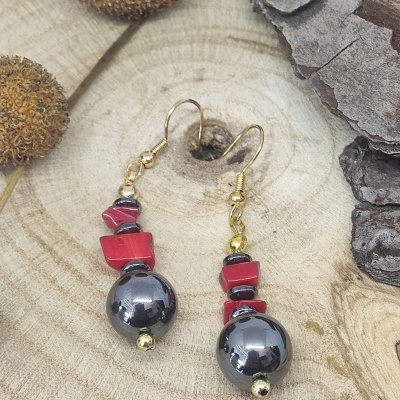 Brincos com pérolas pretas e contas vermelhas sobre tronco de madeira