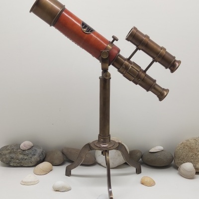 Telescópio vintage com tripé rodeado por pedras e conchas