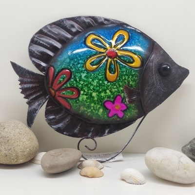 Peixe decorativo em metal colorido com flores, rodeado de pedras e conchas