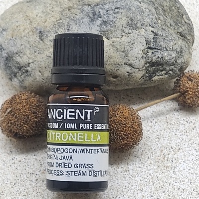 Frasco de óleo essencial de citronela ao lado de pedra e bolinhas secas