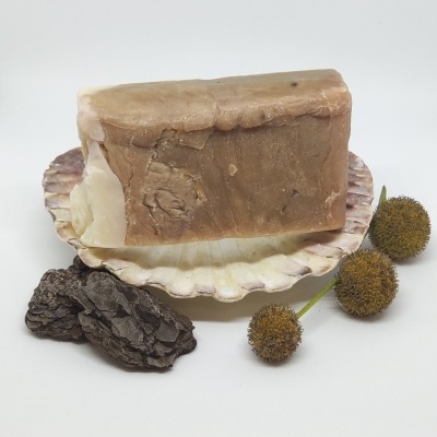 Barra de sabão castanha em concha branca com flores secas e casca