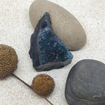 Três pedras e ramo seco em areia clara