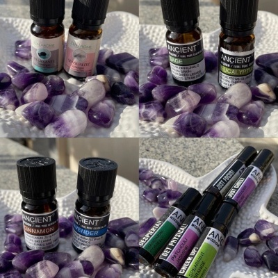 Frascos de óleos essenciais e roll-ons da marca ANCIENT com pedras ametista roxas e brancas
