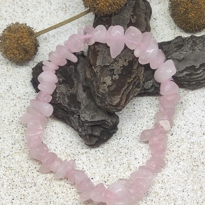 Pulseira de quartz rosa com pedras irregulares sobre fundo claro com casca e frutos secos