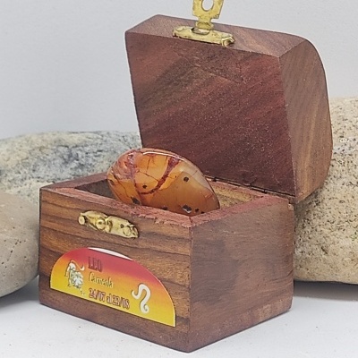 Caixa de madeira aberta com pedra castanha e etiqueta do signo Leão