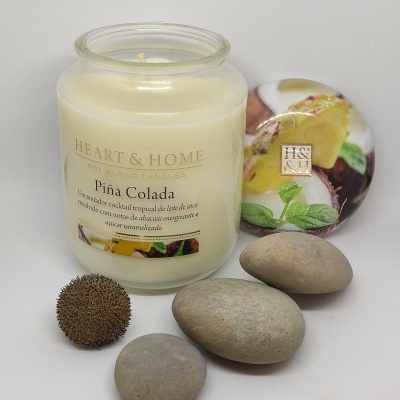 Vela perfumada HEART & HOME Piña Colada em vidro com tampa decorativa e pedras ao lado