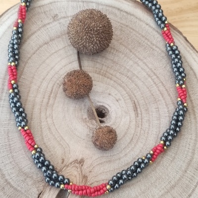 Colar de contas coloridas sobre madeira clara com frutos secos