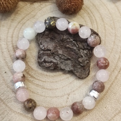 Pulseira de contas coloridas em torno de uma peça de madeira sobre superfície de madeira circular