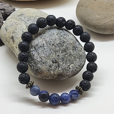 Pulseira de contas negras de lava vulcânica e azuis sobre pedras naturais