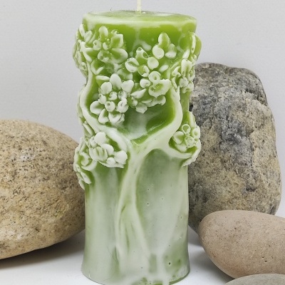 Vela verde decorativa com relevo de árvore e flores entre pedras