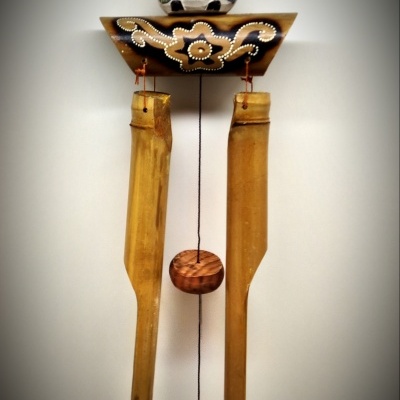 Objeto decorativo de madeira pendurado com coruja pintada e tubos de madeira longa