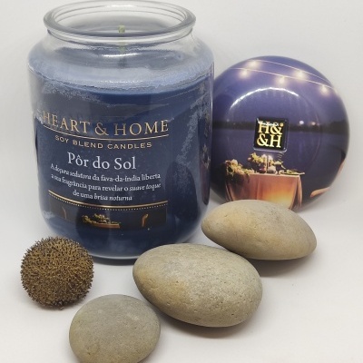 Vela em frasco de vidro azul com tampa roxa, pedras e fruto seco