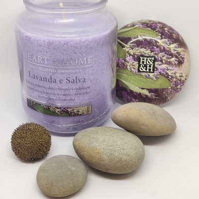 Vela lilás em vidro com tampa de lavanda, pedras cinzentas e planta seca